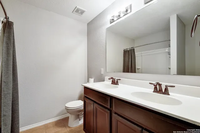 a bathroom with a double vanity sink toilet and a mirror