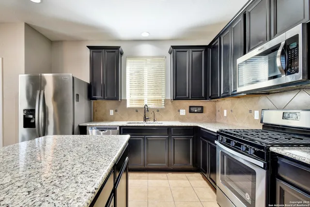 a kitchen with stainless steel appliances granite countertop a sink stove microwave and refrigerator