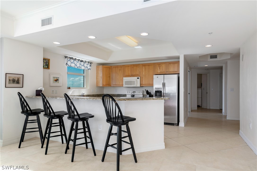 2797 First Street, Unit 1806 Fort Myers, FL 33916 - Photo 8 of 34 a kitchen with stainless steel appliances kitchen island granite countertop a table chairs sink and cabinets