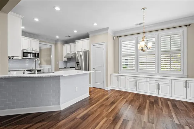 a large kitchen with granite countertop a large counter top space a sink stainless steel appliances and cabinets