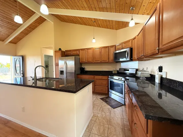 a kitchen with stainless steel appliances granite countertop a sink a stove top oven a counter space and cabinets