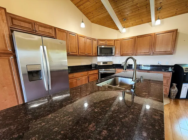 a kitchen with stainless steel appliances granite countertop a sink a stove and a refrigerator