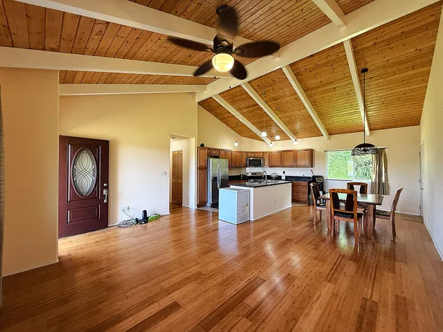 a open kitchen with stainless steel appliances wooden floor dining table and chairs