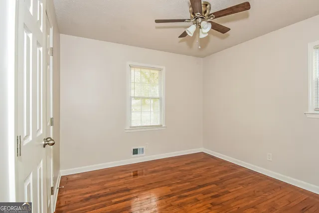 a view of an empty room with wooden floor and a window