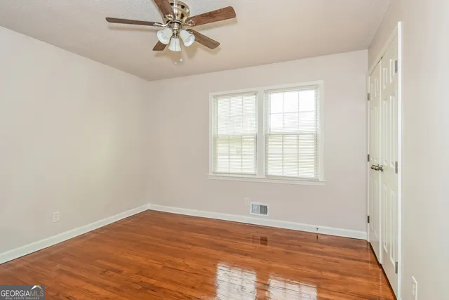 an empty room with wooden floor and windows