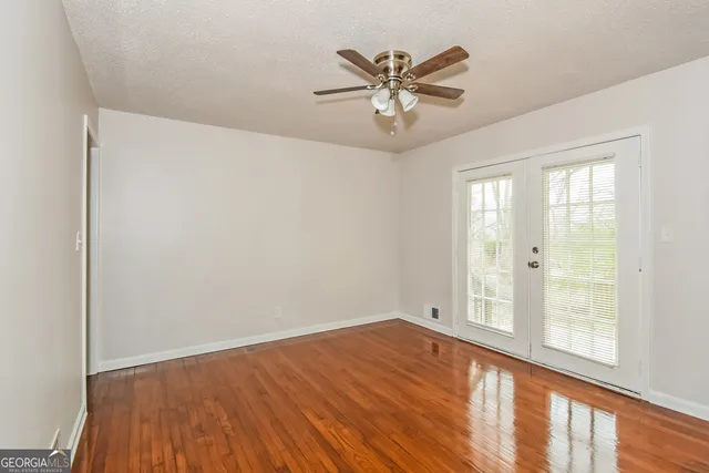 a view of an empty room with wooden floor and a window