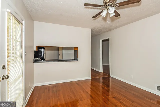 a kitchen with stainless steel appliances granite countertop a refrigerator a sink dishwasher a stove and white cabinets with wooden floor