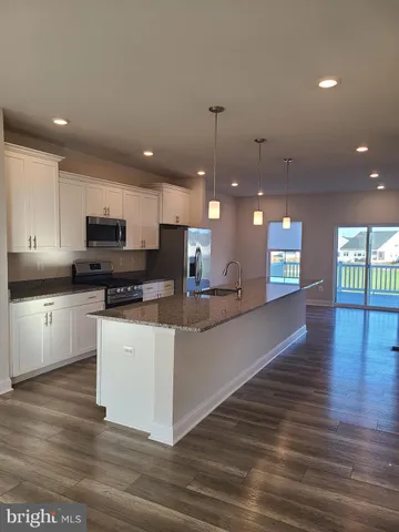 a kitchen with stainless steel appliances granite countertop a sink a stove and a wooden floors