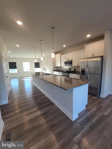 a kitchen with stainless steel appliances granite countertop a sink a stove and a wooden floors