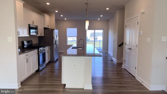 a kitchen with stainless steel appliances kitchen island granite countertop a refrigerator a stove and a sink