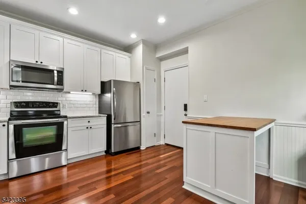 a kitchen with stainless steel appliances a stove a microwave and a hard wood floors
