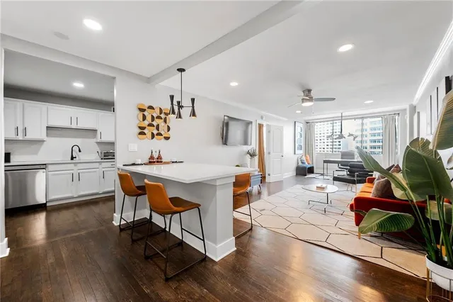 a living room with furniture a wooden floor and kitchen view