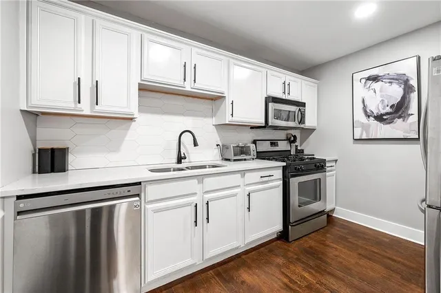 a kitchen with stainless steel appliances granite countertop a sink and cabinets with wooden floor