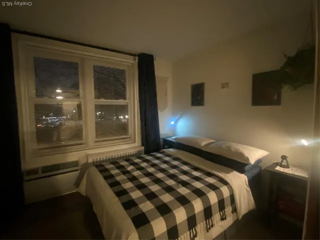 a bedroom with a bed and a lamp next to a window
