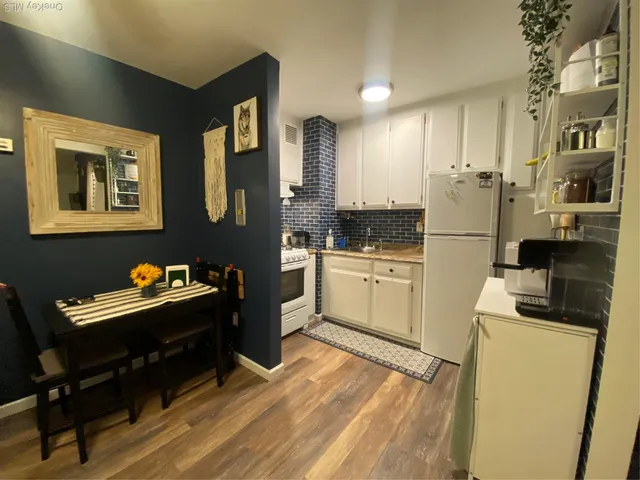 a kitchen with stainless steel appliances kitchen island granite countertop a refrigerator a stove a sink dishwasher and white cabinets with wooden floor