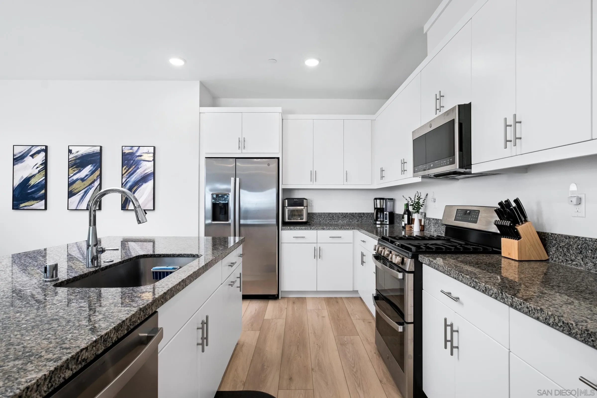 35164 Orchard Trail Fallbrook, CA 92028 - Photo 14 of 52 a kitchen with a sink dishwasher a refrigerator and white cabinets with wooden floor