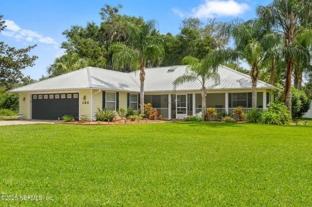 an aerial view of a residential houses with outdoor space and trees all around