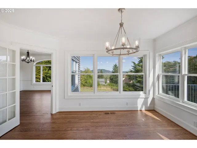 a view of an empty room with wooden floor and windows