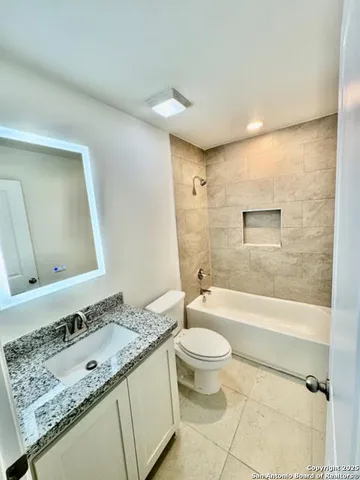 a bathroom with a granite countertop sink toilet mirror vanity and bathtub