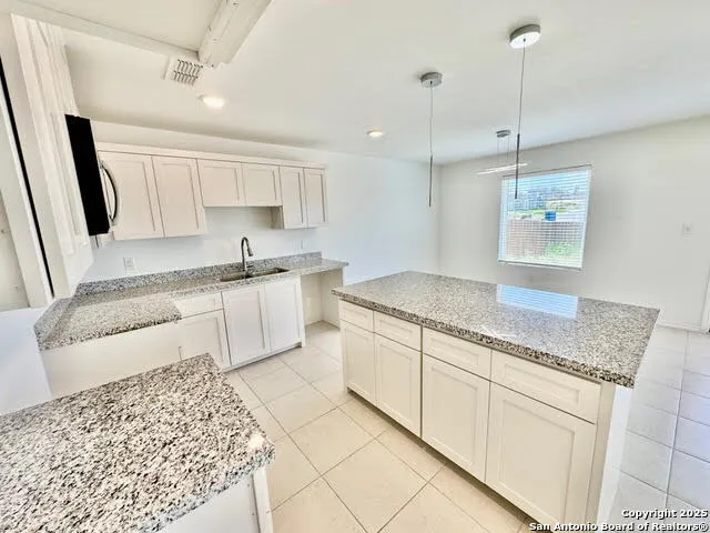 a kitchen with stainless steel appliances granite countertop a sink stove and white cabinets