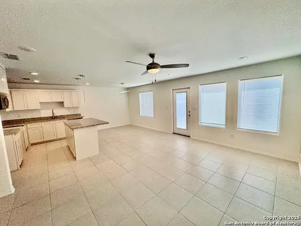 a view of an empty room with kitchen view and a window