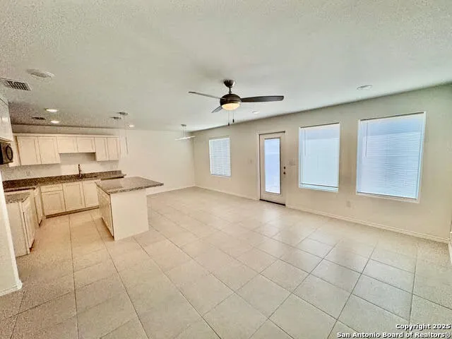 a view of an empty room with kitchen view and a window