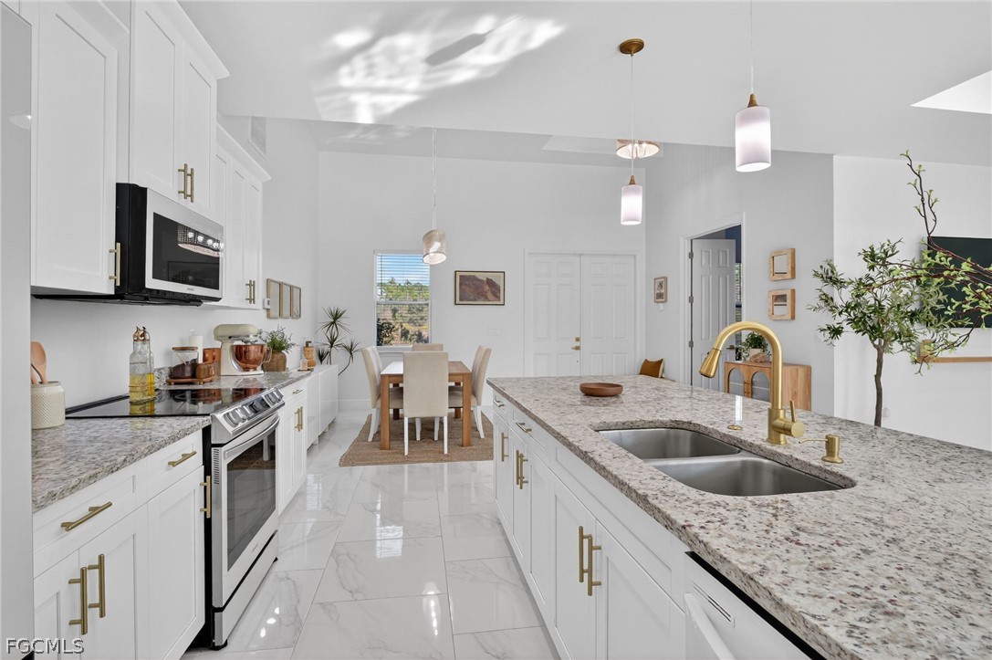 1207 Sheldon Avenue Lehigh Acres, FL 33972 - Photo 11 of 48 a kitchen with granite countertop a sink stainless steel appliances and white cabinets