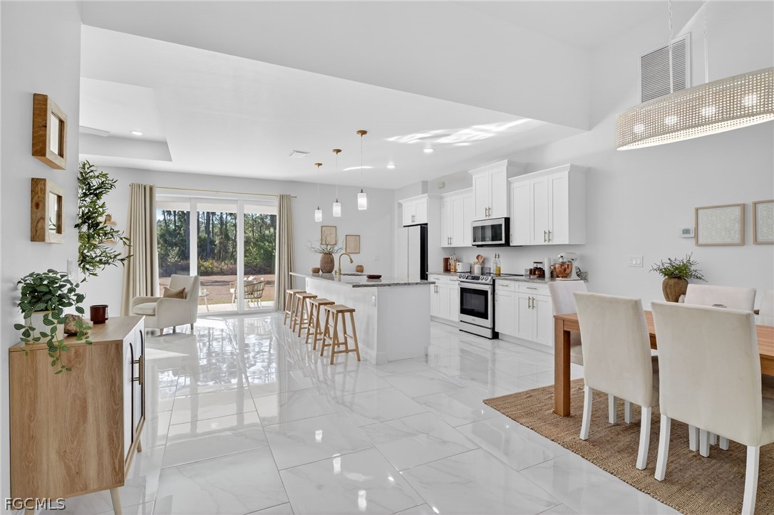 1207 Sheldon Avenue Lehigh Acres, FL 33972 - Photo 4 of 48 a kitchen with white cabinets and dining table chair