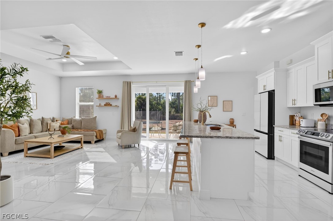 1207 Sheldon Avenue Lehigh Acres, FL 33972 - Photo 5 of 48 a very nice looking living room with stainless steel appliances furniture a chandelier and a view of kitchen