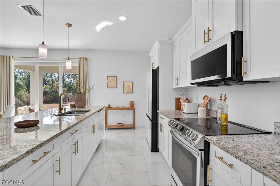 1207 Sheldon Avenue Lehigh Acres, FL 33972 - Photo 7 of 48 a kitchen with stainless steel appliances granite countertop a sink stove and microwave