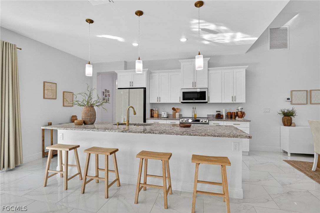 1207 Sheldon Avenue Lehigh Acres, FL 33972 - Photo 9 of 48 a kitchen with white cabinets and chairs