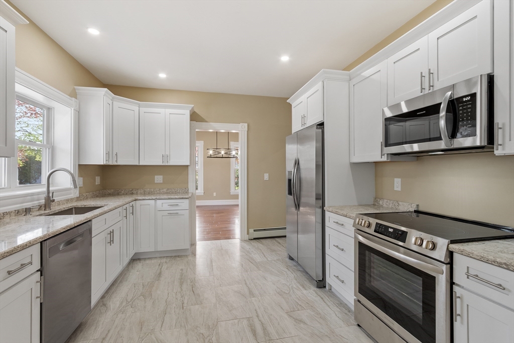 73 Cherry Street Gardner, MA 01440 - Photo 14 of 41 a kitchen with stainless steel appliances granite countertop a stove top oven a sink dishwasher a refrigerator and a microwave oven with wooden floor