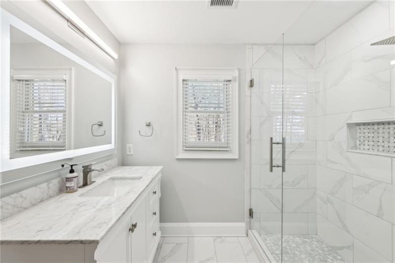 6030 Chimney Springs Road Buford, GA 30518 - Photo 57 of 110 a bathroom with a granite countertop sink a mirror and a shower