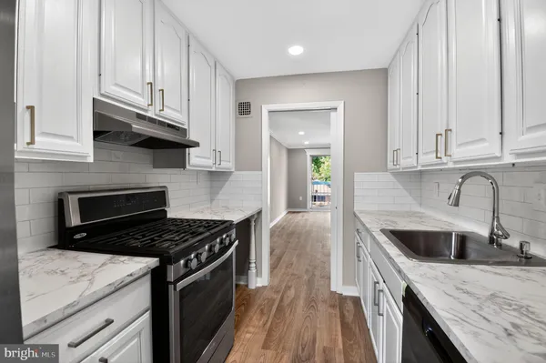 a kitchen with granite countertop a sink a stove and refrigerator