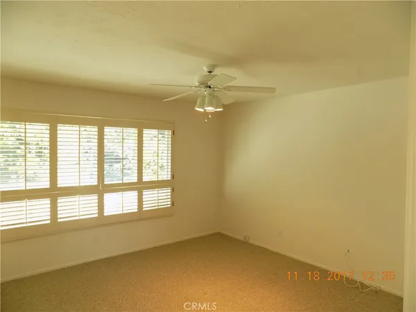 an empty room with a window and a ceiling fan