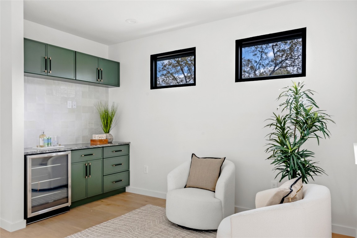 1803 Palo Duro Road Austin, TX 78757 - Photo 24 of 34 Bar featuring green cabinetry, beverage cooler, light wood-type flooring, tasteful backsplash, and light stone counters