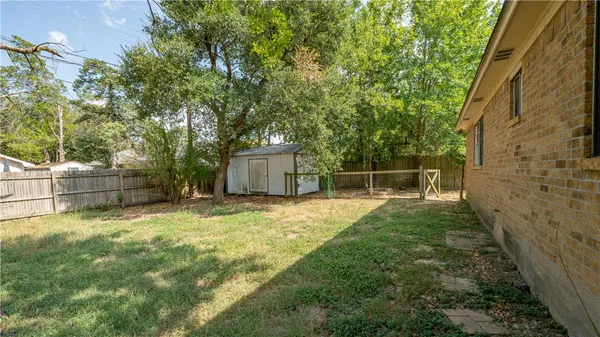 a backyard of a house with large trees and wooden fence