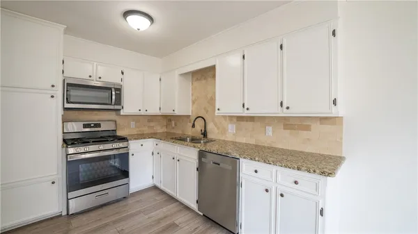a kitchen with granite countertop white cabinets and stainless steel appliances