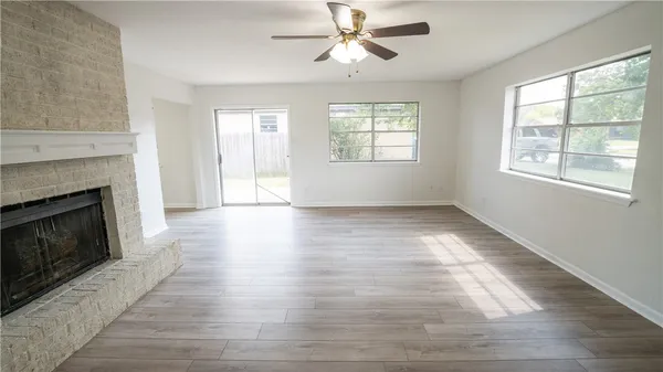 an empty room with wooden floor fireplace and windows