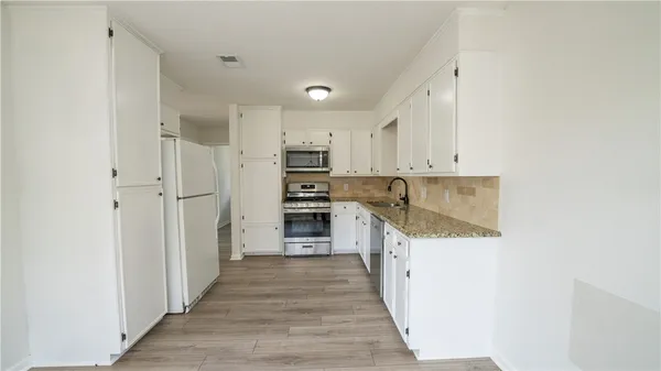 a kitchen with white cabinets and stainless steel appliances