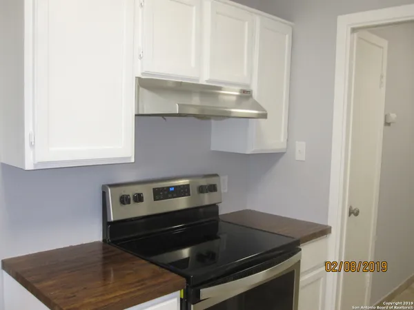 a kitchen with granite countertop a stove and a white cabinets