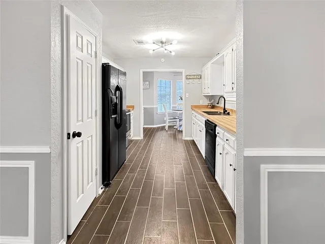 a view of a hallway with wooden floor and a kitchen