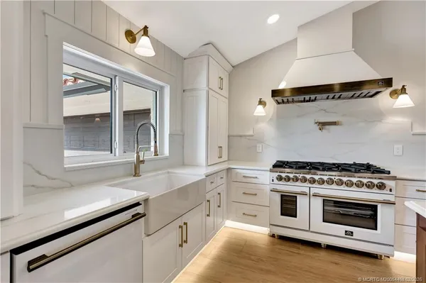 a view of an empty room with wooden floor and a kitchen