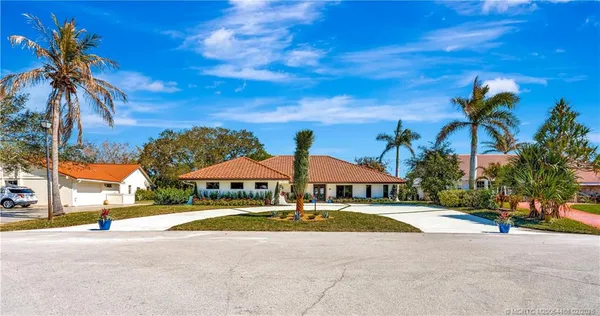 a kitchen with stainless steel appliances granite countertop a refrigerator a sink dishwasher and a dining table with wooden floor