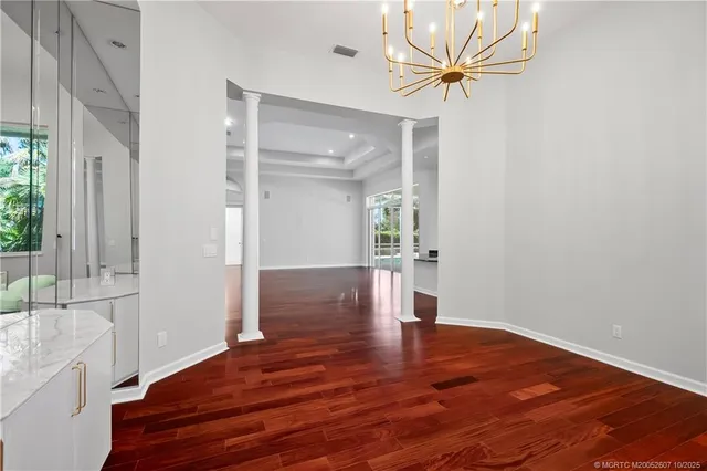a view of an empty room and kitchen with wooden floor