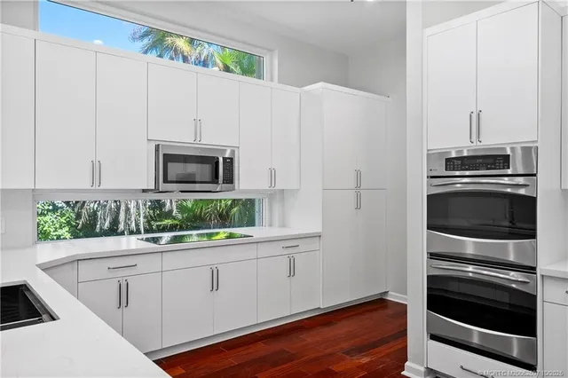 a bathroom with a double vanity sink a mirror and a potted plant