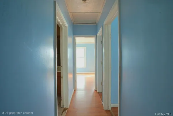 a view of a hallway with wooden floor and a bathroom