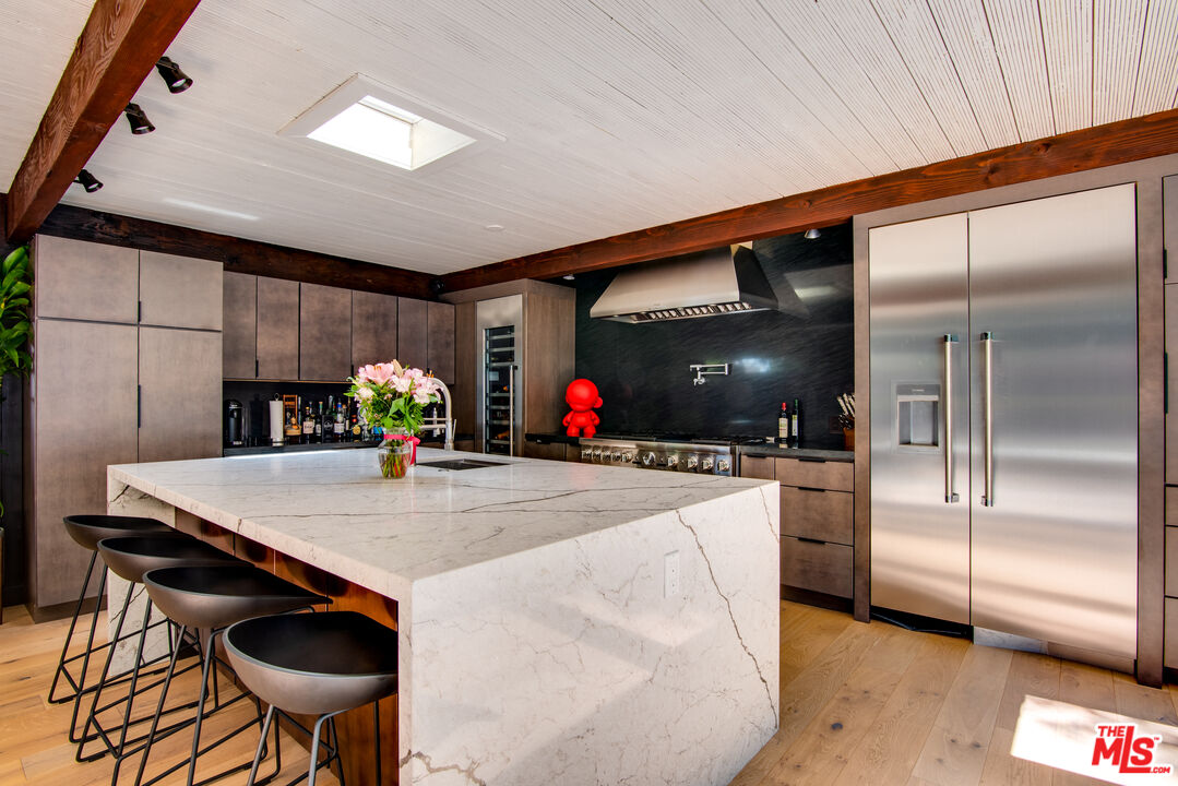 9624 Yoakum Drive Beverly Hills, CA 90210 - Photo 7 of 27 a kitchen with stainless steel appliances kitchen island granite countertop a table and chairs in it