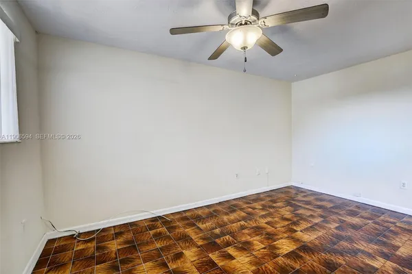 an empty room with a chandelier fan and a window