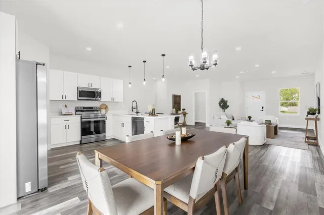 a view of a dining room and livingroom with furniture wooden floor a chandelier